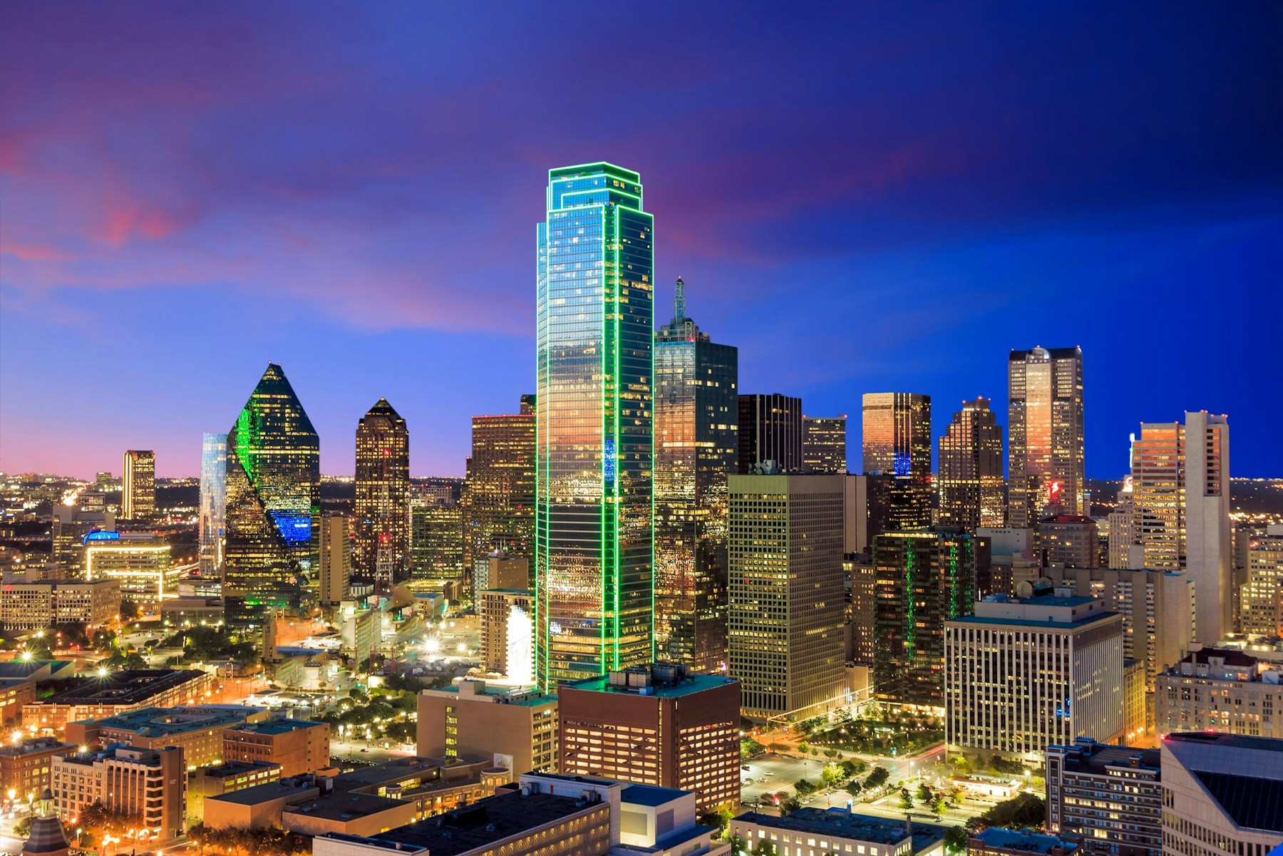 Downtown Dallas illuminated against a deep blue evening sky